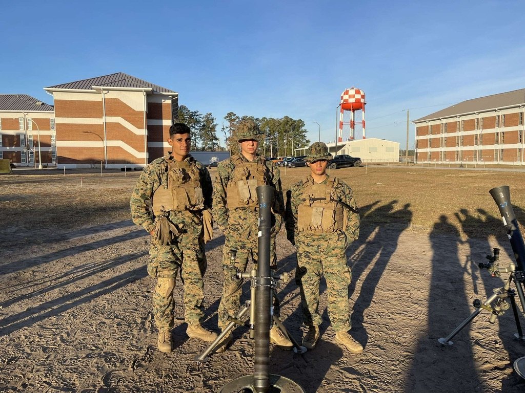Victor Kiani in camouflage standing beside a mortar, with two other Marines.